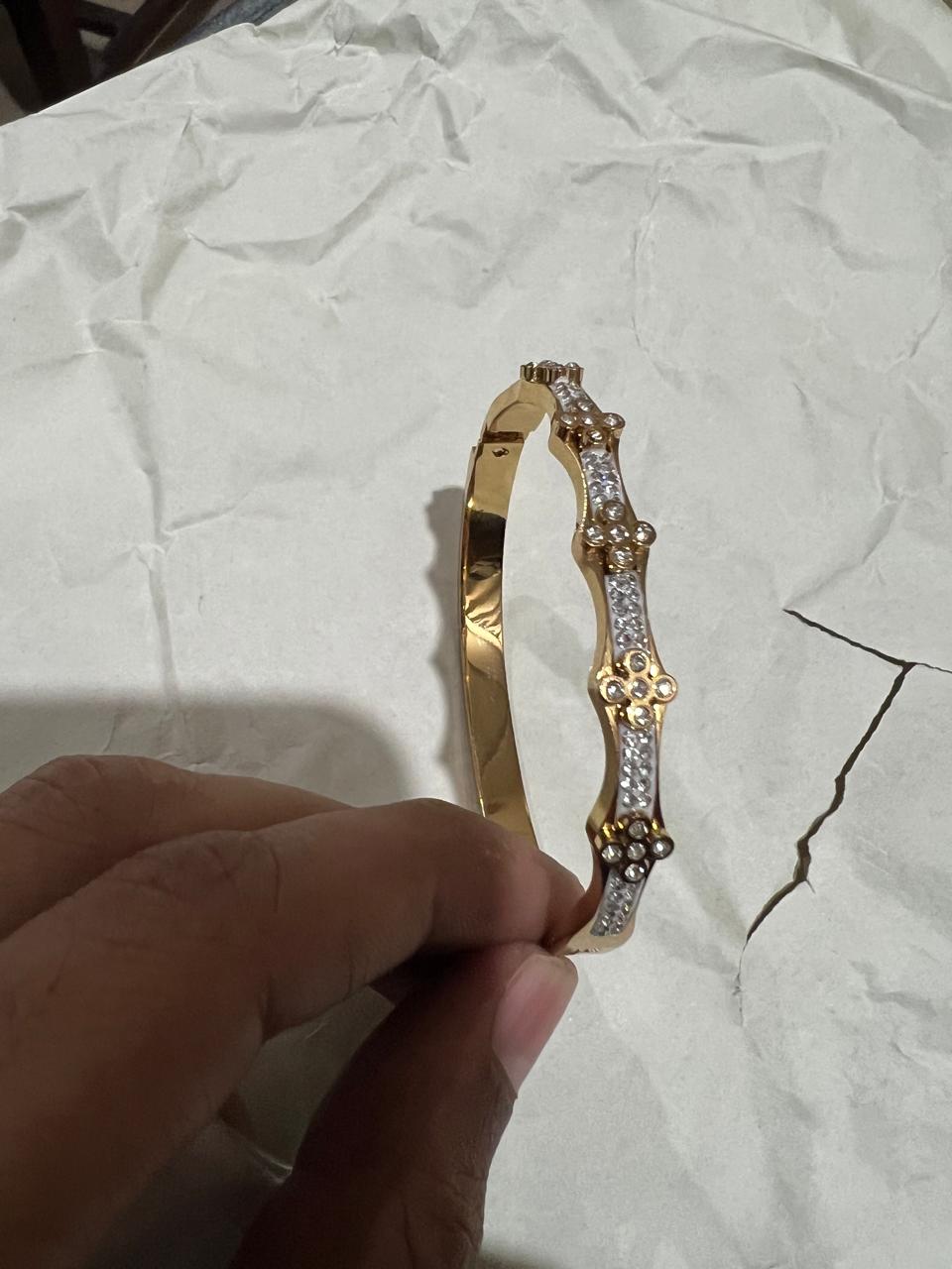 Gold wavy crystal bangle bracelet held in hand