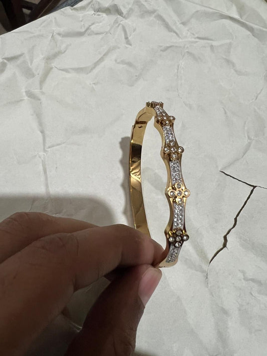 Gold wavy crystal bangle bracelet held in hand