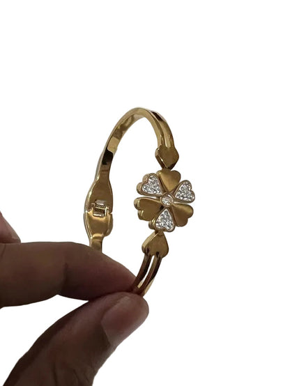 Gold four-leaf clover crystal cuff bracelet held in hand