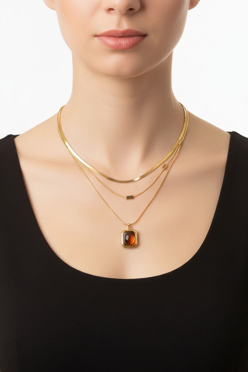 Model wearing gold layered snake chain necklace with amber pendant